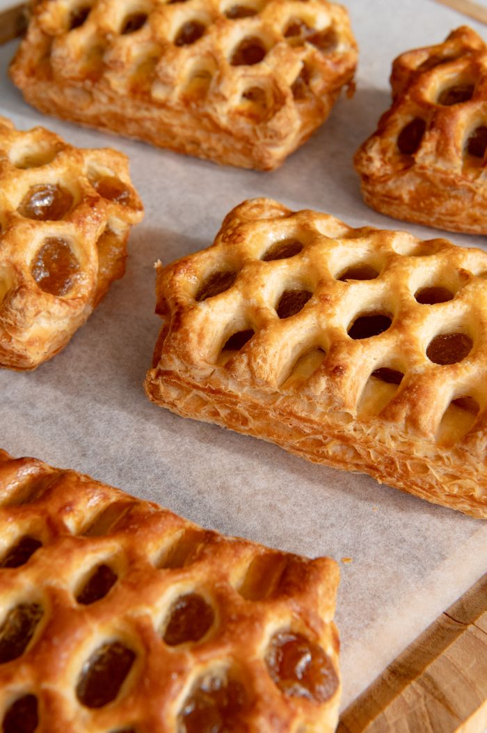 services-09 Freshly baked lattice pastries arranged on parchment paper, showcasing golden brown, flaky texture.