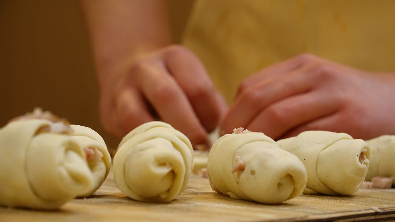 Mastering the First Impression: Your intriguing post title goes here Hands expertly rolling dough in a bakery kitchen, ready for baking.