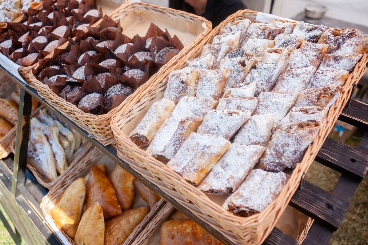 services-09 A variety of fresh pastries, including strudels and muffins, arranged in wicker baskets at a market display.